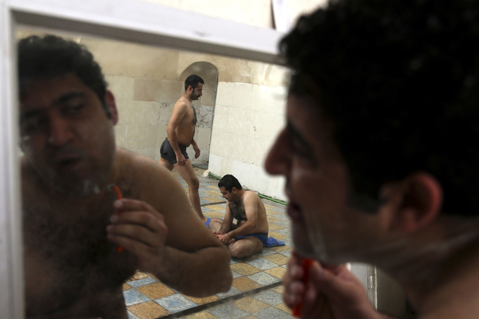 مردی در یک حمام سنتی صورتش را اصلاح می کند